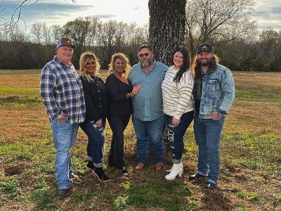 The entire family is posing Infront of a Tree as Koe Wetzel is standing next to Zoie Wetzel, then his father, Julie Wetzel, Presleigh Wetzel and at far left Brantley Womack.